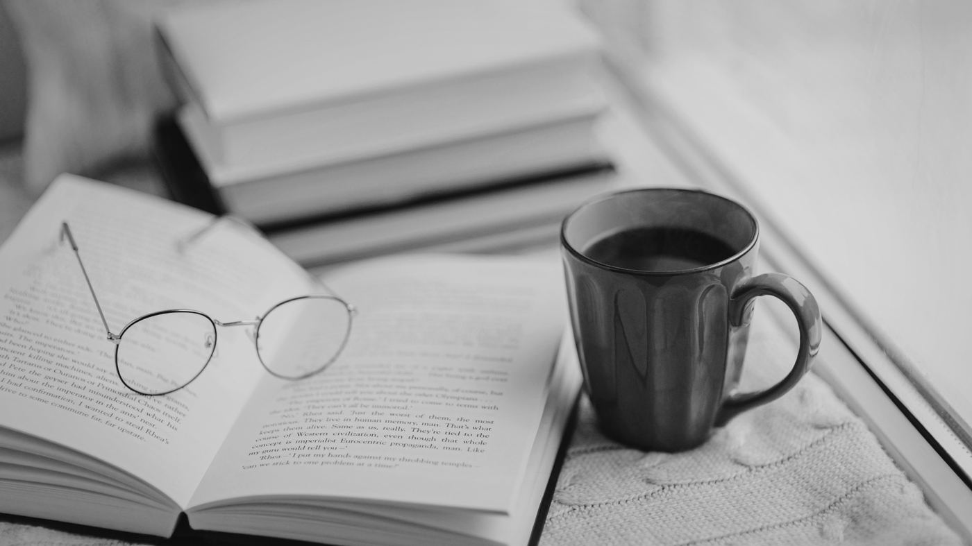 Open book with reading glasses and a cup of coffee